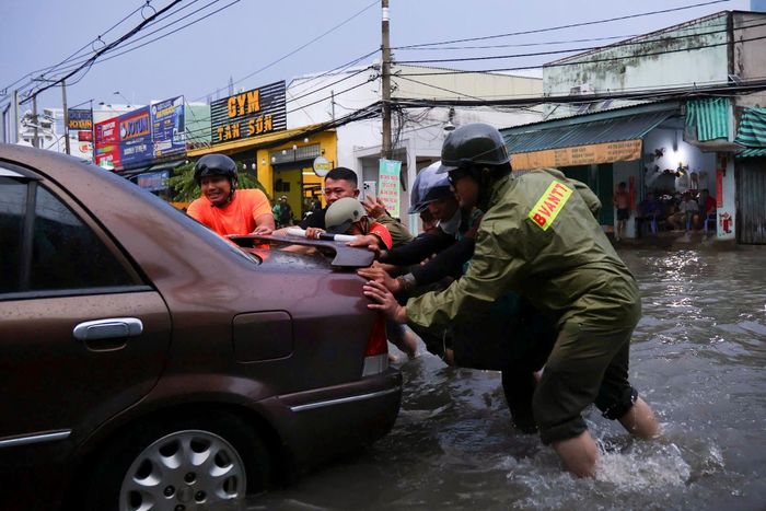 Lực lượng Bảo vệ An ninh cơ sở phường Bình Trị Đông hỗ trợ đẩy xe ôtô chết máy qua đoạn ngập. Ảnh: Võ Kỳ.