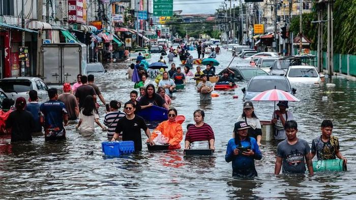 Người dân lội qua một con đường ngập nước ở Bangkok, Thái Lan - Ảnh: Reuters