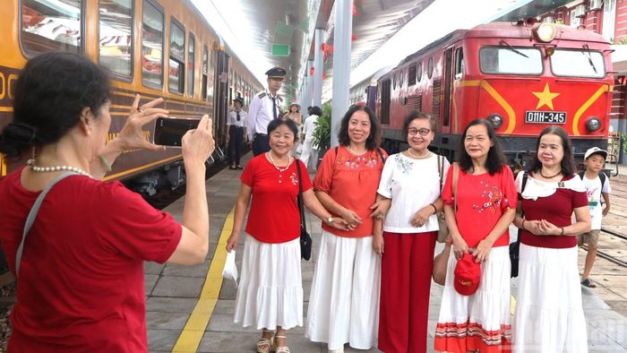 Nhóm du khách ghi lại tấm hình lưu niệm giữa 2 đoàn tàu kết nối 2 hành trình di sản: Cố đô Huế-Phong Nha và Huế-Đà Nẵng tại ga Huế. (Ảnh: HG)