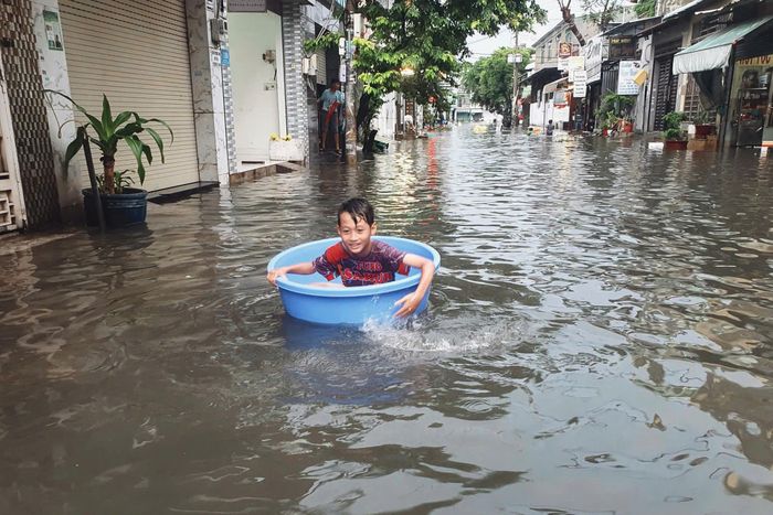  Trẻ em lấy thau làm "thuyền" trên đường 14, phường Bình Hưng Hòa. Ảnh: Kiên Cường 