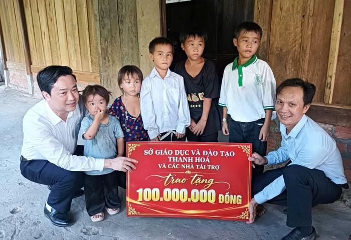 Ông Đỗ Đức Quế (trái), Giám đốc Sở GD&ĐT Thanh Hóa trao biển tượng trưng phần tiền đến 5 em nhỏ ở bản Cánh Cộng, xã vùng biên Trung Lý.