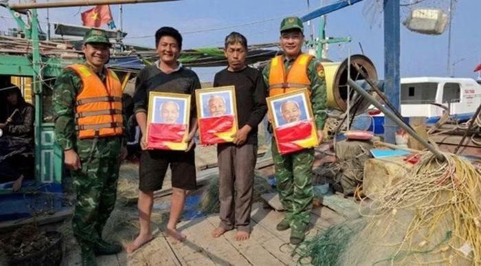 Cán bộ, chiến sỹ trao ảnh Bác Hồ và cờ Tổ quốc tặng ngư dân hoạt động trên vùng biển Đảo Trần. (Ảnh: Tư liệu Đồn Biên phòng Đảo Trần)