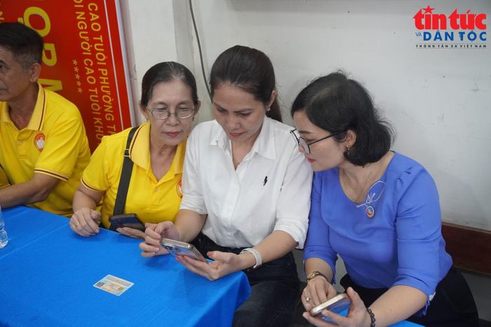 Bà Đào Thị My Thư, Phó Bí thư Đảng ủy, Chủ tịch UBND phường Thông Tây Hội (bìa phải) đang theo dõi các thao tác ứng dụng số của người dân.