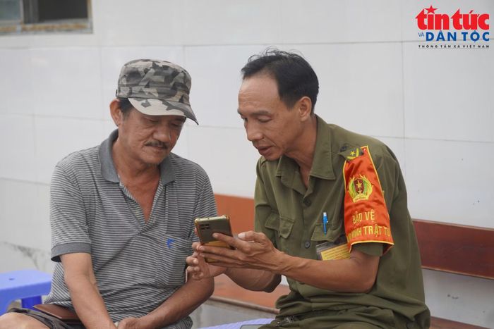 Ông Trần Văn Dũng được cán bộ địa phương hướng dẫn cập nhật các thông trên ứng dụng số.