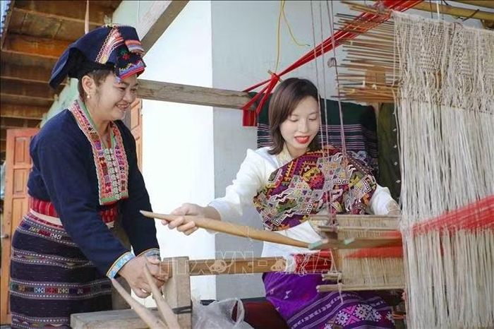Chị Lò Thị Vân hướng dẫn du khách trải nghiệm dệt thổ cẩm của người Lào. Ảnh: Xuân Tư/TTXVN
