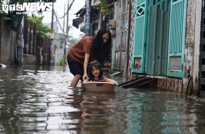 Nước ngập sâu khiến nhiều xe máy chết máy. Để di chuyển qua những đoạn ngập, người dân phải sử dụng chậu hoặc các vật dụng nổi tạm thời.