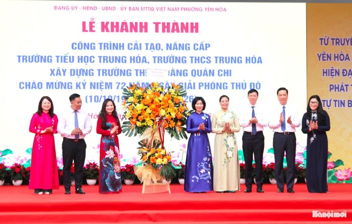 Phó Bí thư Thành ủy, Chủ tịch HĐND thành phố Hà Nội Phùng Thị Hồng Hà, cùng đại diện lãnh đạo các sở, ngành thành phố, lãnh đạo phường Yên Hòa tặng hoa chúc mừng Ban Giám hiệu trường THCS Trung Hòa. Ảnh: Vân Nhi