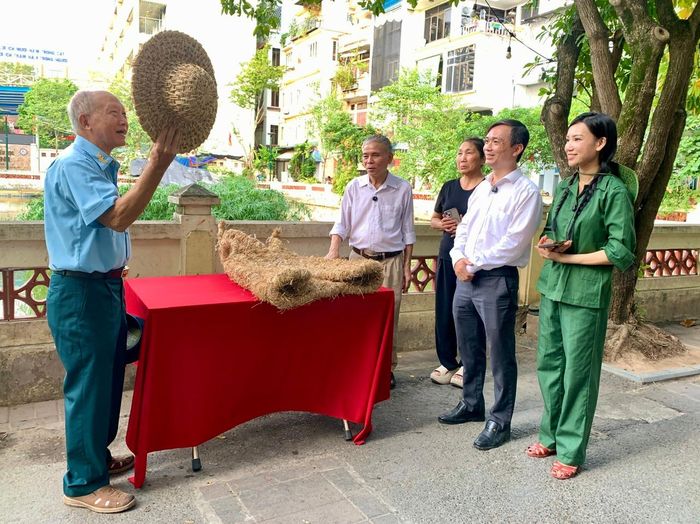 Đại tá Vũ Đình Rạng (trái) giới thiệu về chiếc mũ rơm mà người dân đã từng dùng để hạn chế sát thương của mảnh bom, pháo. Ảnh: PV