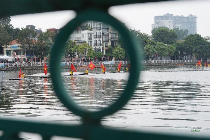Đoàn SUP mang cờ Tổ quốc di chuyển qua mặt hồ Tây, nhìn từ phía lan can ven bờ. Ảnh: Tuấn Anh