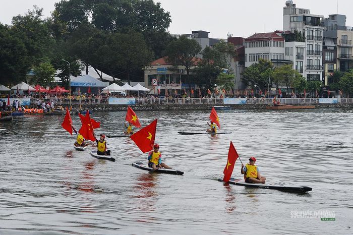 Những lá cờ đỏ sao vàng tung bay trên các tấm ván SUP trong màn diễu hành. Ảnh: Tuấn Anh