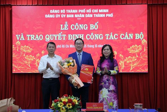 Bà Nguyễn Thanh Xuân, Phó Bí thư Đảng ủy, Trưởng Ban Xây dựng Đảng Đảng ủy UBND TP.HCM trao quyết định và ông Nguyễn Hữu Đạt, Trưởng Cơ quan đại diện Văn phòng Bộ VHTTDL tại TP.HCM tặng hoa chúc mừng ông Trịnh Đăng Khoa