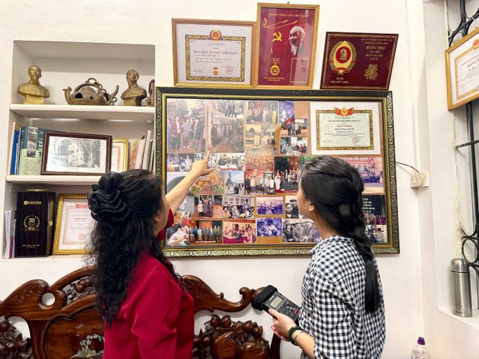 Bà Phạm Thị Viễn (bên trái) giới thiệu những bức ảnh thời chiến được bà treo trang trọng trên tường nhà. Ảnh: NGỌC THANH 