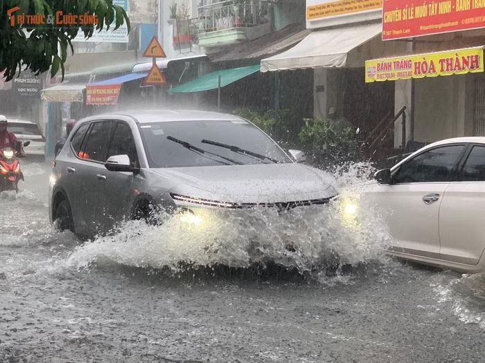 Ô tô rẽ "sóng nước" trên đường ngập trong chiều cuối tuần sau cơn mưa lớn ở TP HCM.