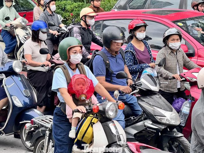 Một phụ nữ chở con nhỏ chờ di chuyển qua khu vực ùn ứ tại nút giao Bưởi - Võ Chí Công - Hoàng Quốc Việt.
