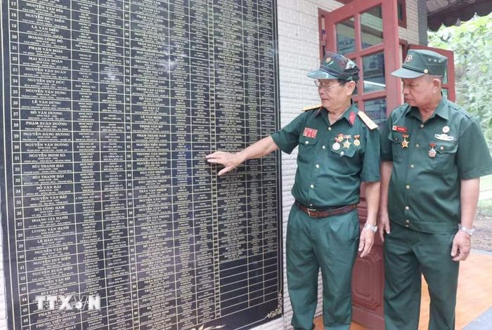 Cựu chiến binh Vũ Đức Ninh cùng đồng đội xem lại tên những người đồng đội đã mất trong chiến tranh được khắc tên trang trọng tại nhà bia tưởng niệm tại phường Hố Nai, thành phố Đồng Nai. (Ảnh: Lê Xuân/TTXVN)