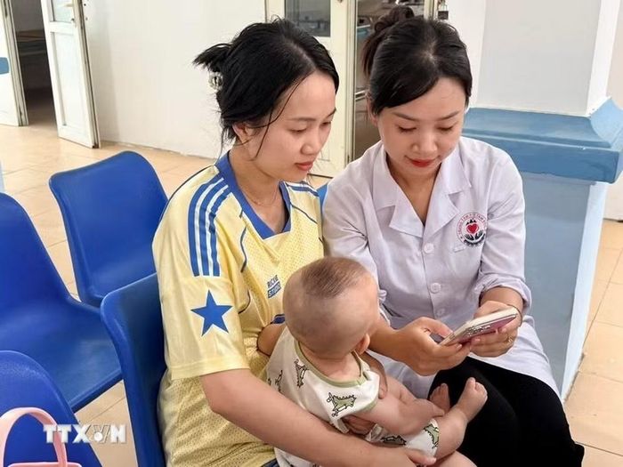 Nhân viên Trạm y tế xã Đạo Trù hướng dẫn người bệnh cài đặt và sử dụng Sổ sức khoẻ điện tử trên VNeID. (Ảnh: Nguyễn Thảo/TTXVN)