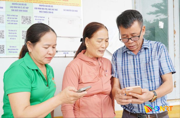 Cán bộ tổ dân phố Trà Cai hướng dẫn bà Huỳnh Thị Bộ (ở giữa) đăng nhập tài khoản VNeID và tích hợp các loại giấy tờ tùy thân. Ảnh: N.ĐOAN