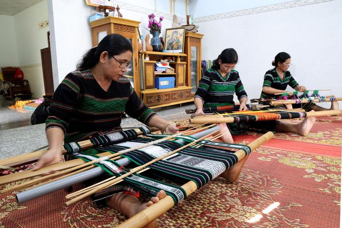 Chị H’ Yôn (ngồi giữa) cùng các thành viên Tổ hợp tác dệt thổ cẩm bon Pi Nao