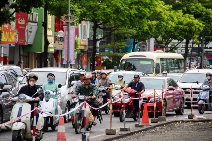 Người dân di chuyển qua đoạn phố Ô Chợ Dừa đang thi công xén dải phân cách.
