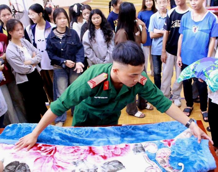 Chiến sĩ Trung đoàn 584 hướng dẫn học sinh Trường PTDTNT THPT N’Trang Lơng thực hành gấp chăn, rèn luyện nền nếp, tác phong trong sinh hoạt hàng ngày. Ảnh: Y Lam Niê