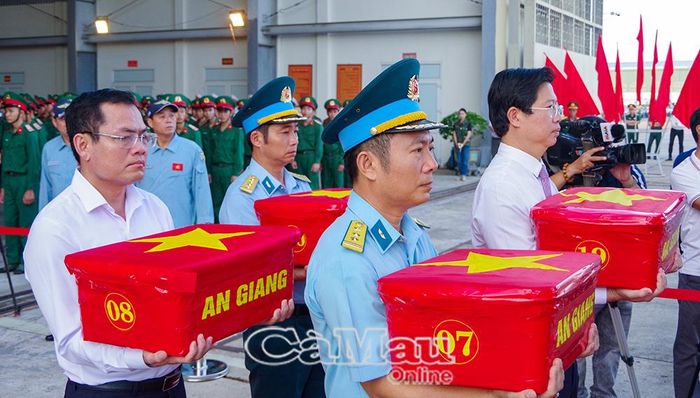 Phó Chủ tịch UBND tỉnh Cà Mau Ngô Vũ Thăng (bìa trái) đưa mẫu hài cốt liệt sĩ lên máy bay.