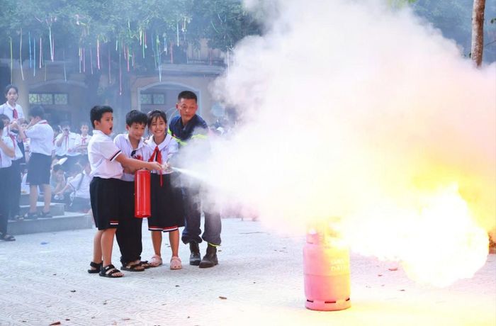 Các em học sinh được hướng dẫn thao tác sử dụng bình chữa cháy