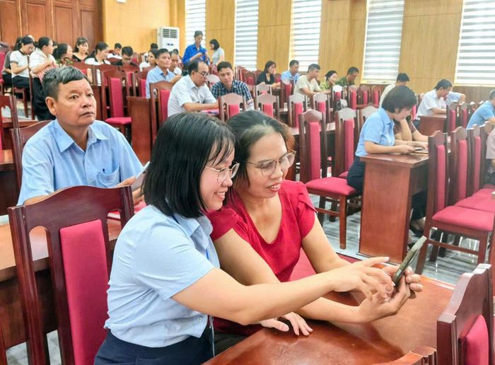 Cán bộ hướng dẫn người dân các thao tác ứng dụng VNeID trên điện thoại.