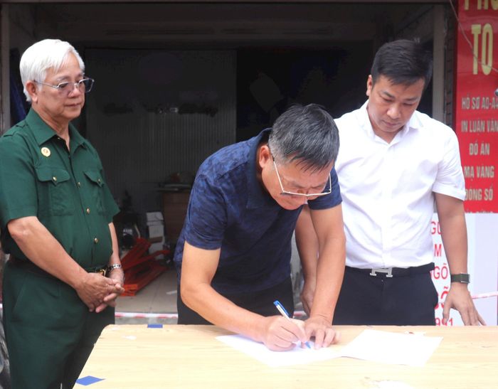 Ông Quách Văn Minh (áo xanh) và đại diện Ban QLDA đầu tư - hạ tầng phường Bạch Mai ký biên bản bàn giao mặt bằng tại số 77 đường Giải Phóng dưới sự chứng kiến của lãnh đạo UB MTTQ Việt Nam phường và cán bộ Ban, tổ dân phố. Ảnh: PV
