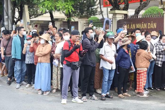 Nhiều người đứng sát hàng rào tòa án, dùng điện thoại ghi lại diễn biến bên ngoài phiên xử. (Ảnh: Văn Quân/ TPO)