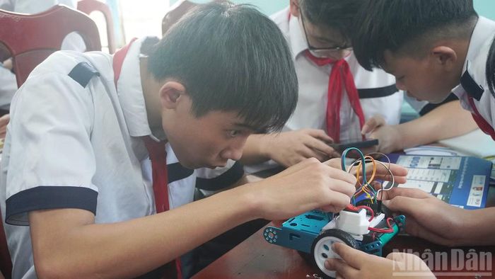 Các em học sinh lên ý tưởng và thực hành lắp ráp robot. (Ảnh: THANH TÂM)