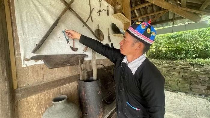 Trưởng bản Chá A Mua giới thiệu với du khách các dụng cụ sản xuất mang đậm bản sắc văn hóa dân tộc Mông bản Tù Lu-Tìa Ló. (Ảnh: LÊ LAN)