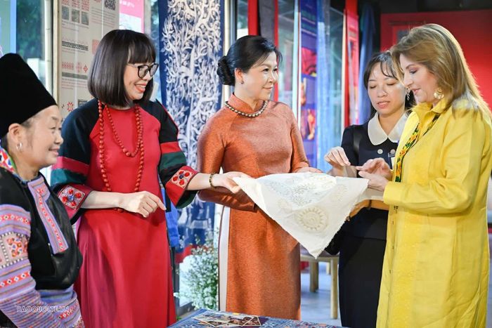 Hai Phu nhân nghe giới thiệu về tấm vải với hoa văn vẽ bằng sáp ong cùng những ý nghĩa của các họa tiết. (Ảnh: Nguyễn Hồng)
