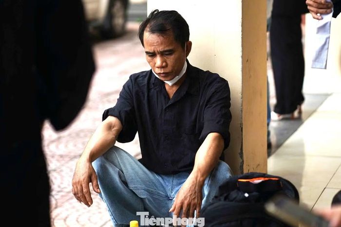 Người nhà nạn nhân ngồi lặng lẽ ở một góc tường trong khuôn viên tòa án trước giờ xét xử.