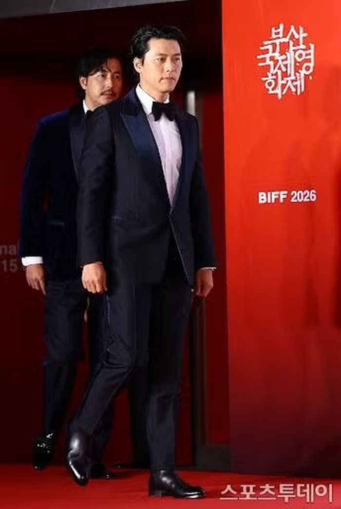 Hyun Bin lịch lãm với vest tối màu, phối cùng sơ mi trắng, nơ và giày da đen bóng loáng.