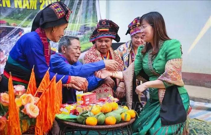 Du khách trải nghiệm nghi thức buộc chỉ cổ tay tại Tết té nước của đồng bào Lào vào tháng 4 hàng năm ở Thanh Yên. Ảnh: Xuân Tư/TTXVN