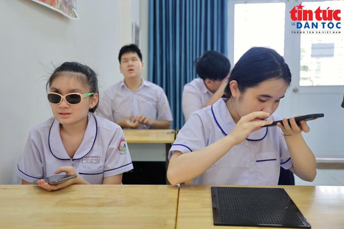 Em Trần Hoàng Hải Lam (bên trái), học sinh lớp 9, chia sẻ sự thích thú với các tính năng hỗ trợ nhận biết mệnh giá tiền, màu sắc và đọc văn bản của ứng dụng.