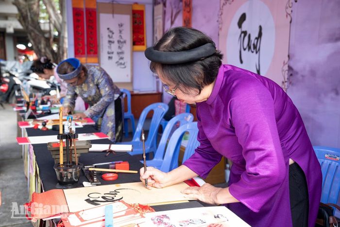 Thành viên Câu lạc bộ Đông Hồ viết thư pháp tặng người dân và du khách.