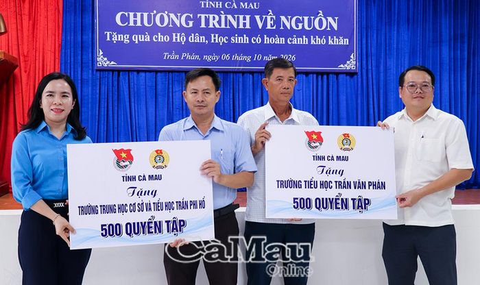 Phó Chủ tịch Thường trực Liên đoàn Lao động tỉnh Ngô Diễm Phúc (bìa trái) và ông Trần Hoàng Khởi, Chủ tịch UBND Xã Trần Phán (bìa phải), trao tập cho đại diện các trường học.