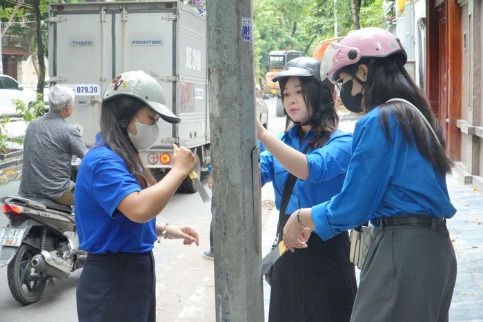 Lực lượng đoàn viên thanh niên phường tham gia bóc, xóa quảng cáo, rao vặt trái quy định. Ảnh: Huy Hoàng