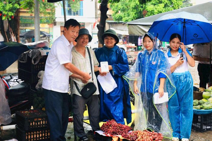 Cán bộ thôn Bình Vọng tham gia tuyên truyền, vận động tiểu thương kinh doanh trên địa bàn giao dịch không sử dụng tiền mặt. Ảnh: PV