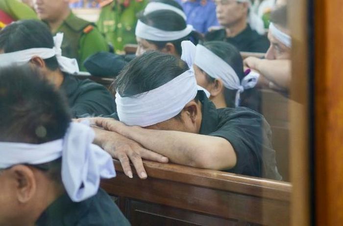 Tại phiên tòa, người thân của các nạn nhân không kìm được nỗi đau, liên tục cúi xuống bàn khi nghe những nội dung trong bản cáo trạng. Ảnh: ĐS&PL