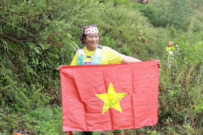 Nữ nhà báo tranh thủ chụp ảnh lưu niệm cùng lá cờ Tổ quốc