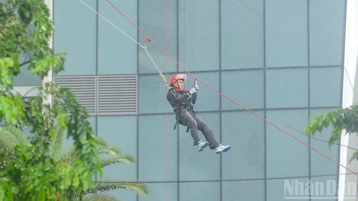 Trong ảnh là phương án cán bộ, chiến sĩ nhanh chóng triển khai đội hình cầu dây nghiêng. Đội hình cứu người bằng cầu dây nghiêng được sử dụng trong các tình huống cứu người trên cao trong điều kiện đường và lối thoát nạn bị hạn chế do sập đổ, bị ảnh hưởng bởi nhiệt độ cao hoặc khói, khí độc bao trùm; người bị nạn không thể thoát nạn theo các đường thoát nạn khác. (Ảnh: CÔNG VINH)