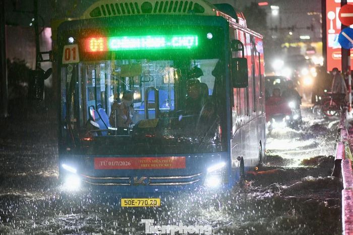 Xe buýt di chuyển chậm qua đoạn đường ngập nước trên đường R12.