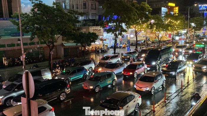 Hàng dài ô tô nối đuôi nhau di chuyển chậm qua khu vực nút giao Hàng Xanh trong cơn mưa lớn.