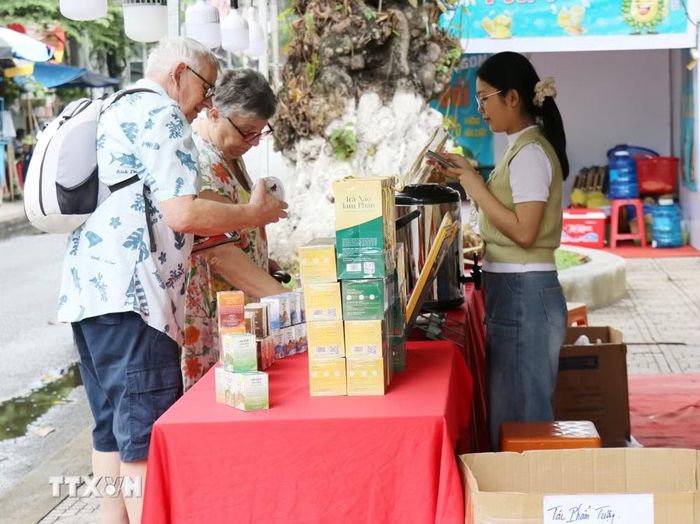 Du khách nước ngoài chọn mua sản phẩm đặc sản tại một sự kiện giới thiệu, quảng bá sản phẩm OCOP do tỉnh Khánh Hòa tổ chức. (Ảnh: Nguyễn Thành/TTXVN)