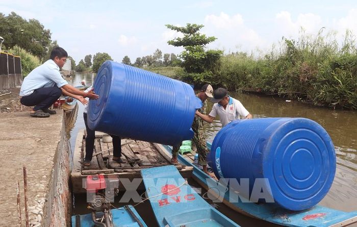 800 hộ dân thiếu nước sinh hoạt được nhận dụng cụ chứa nước về nhà trong đợt này. Ảnh: Tuấn Phi - TTXVN