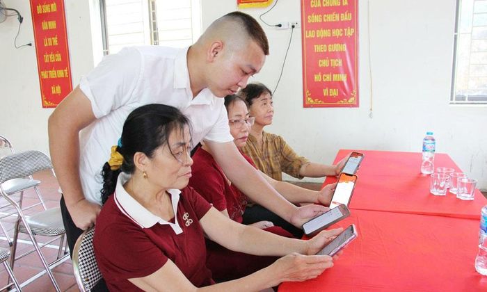 Đảng viên trẻ Chi bộ tổ dân phố Tiền Ngoài, phường Hạp Lĩnh hướng dẫn các đảng viên trong chi bộ sử dụng Sổ tay đảng viên điện tử.