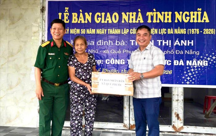 Lãnh đạo xã Quế Phước tặng quà cho gia đình bà Trần Thị Ánh tại lễ bàn giao nhà. Ảnh: MINH THÔNG