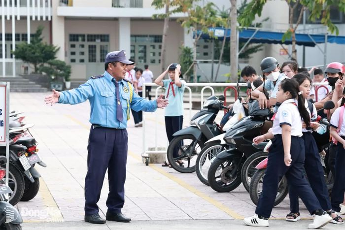 Bảo vệ của nhà trường hướng dẫn phụ huynh và học sinh ra về an toàn. Ảnh: Công Nghĩa